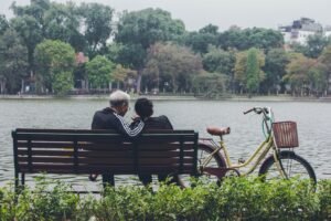 An elderly couple sits by a serene lake in Hanoi, embracing nature and tranquility.